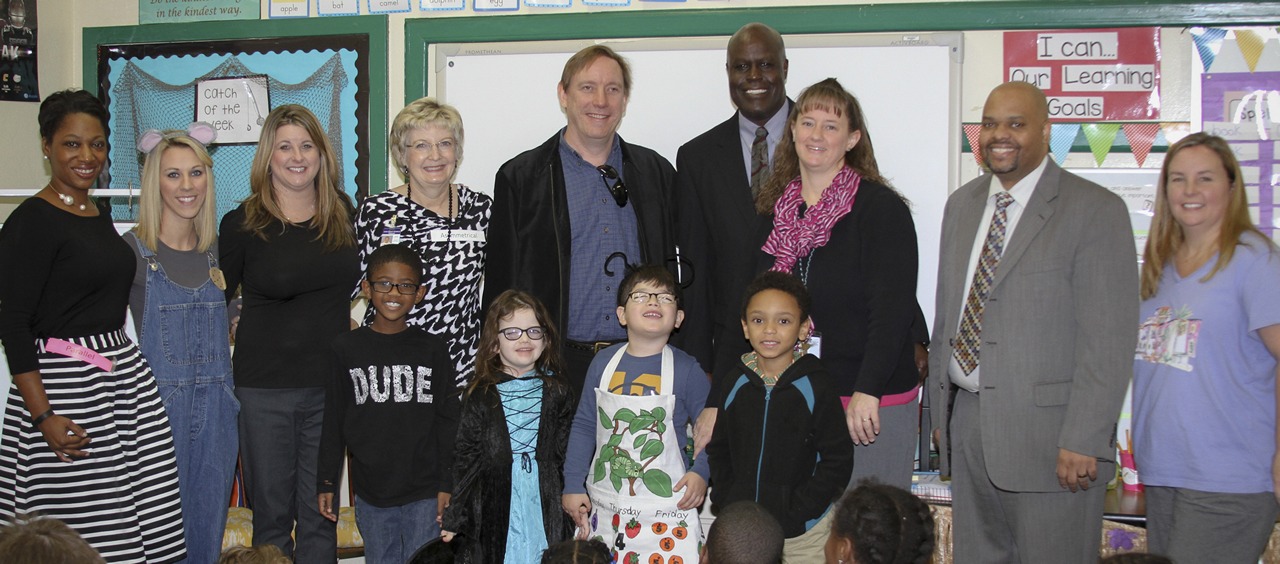 Assistant Principal Sylvia Myers, Teacher Emily Avery, Assistant Principal Dawn Wilder, Principal Pam Stephens, Division of Blind Services staff member Adam Gaffney, K-12 Public Schools Chancellor Hershel Lyons, Teacher Heather Riblett, Director of Division of Blind Services Robert L. Doyle, and Vision Teacher Teri Newsome pose with first grade students at Kate Sullivan Elementary School. The group enjoyed several activities in honor of Braille Literacy Month.