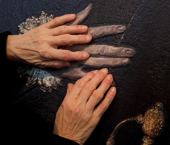 Two hands feeling 3-D artwork