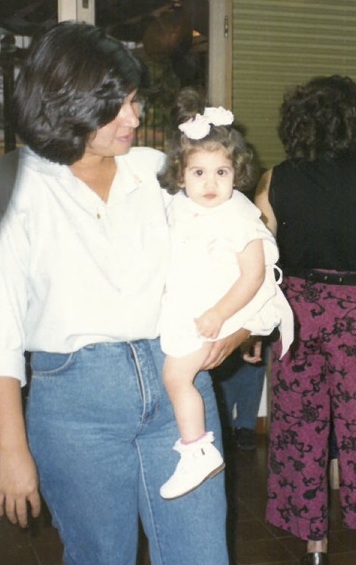 Toddler in a white dressed being held by her aunt.