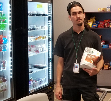 Vendor standing in front of coolers holding a bag.