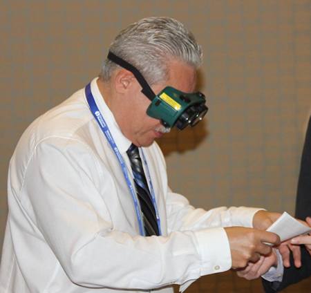 See different attendee looking through vision simulator glasses.