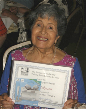 A woman, Leonor Ackerson, smiling as she holds a certificate