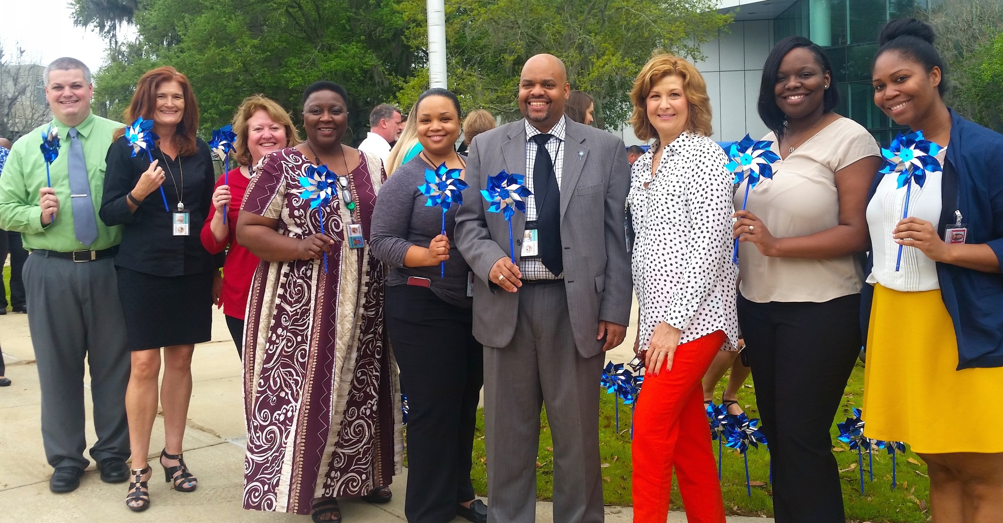 DBS Staff standing in front of the Turlington Building holding blue and silver pinwheels