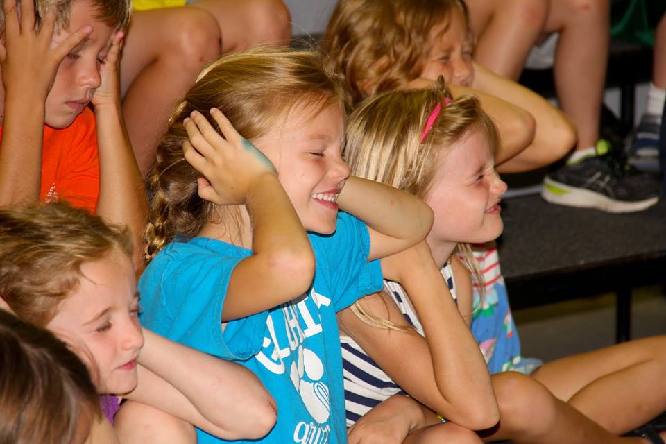 Young students with their eyes closed and hands over their ears
