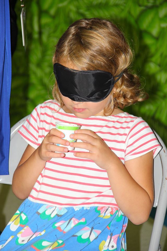 Female student smelling a food item in a cup while blindfolded