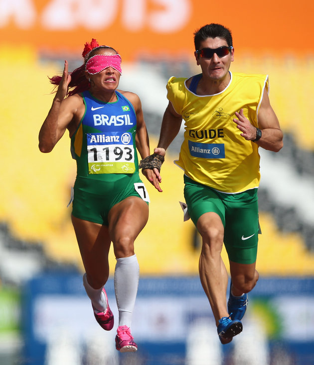 Guilhermina is held by her guide as she runs in a race