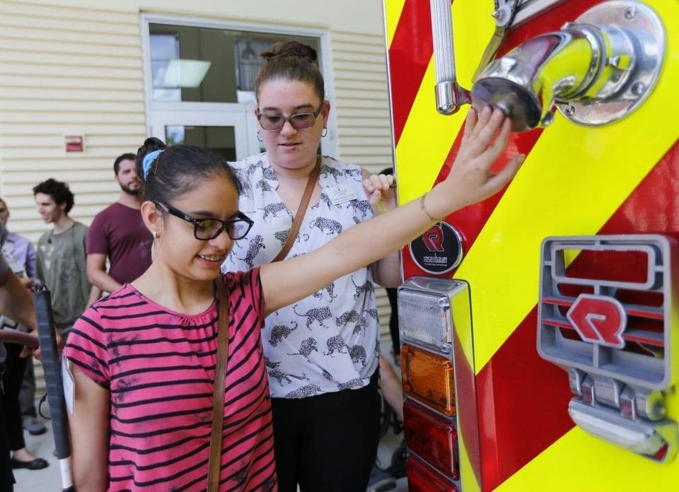 Visually Impaired female student feels the front of a firetruck. 