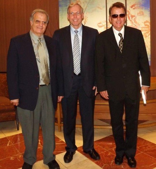 Tom Spiliotis, Bill Findley and Don Tuell wearing suits and standing in the lobby of a hotel