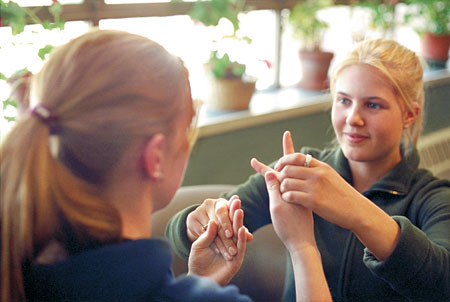 Woman doing sign language into another woman’s hands. 