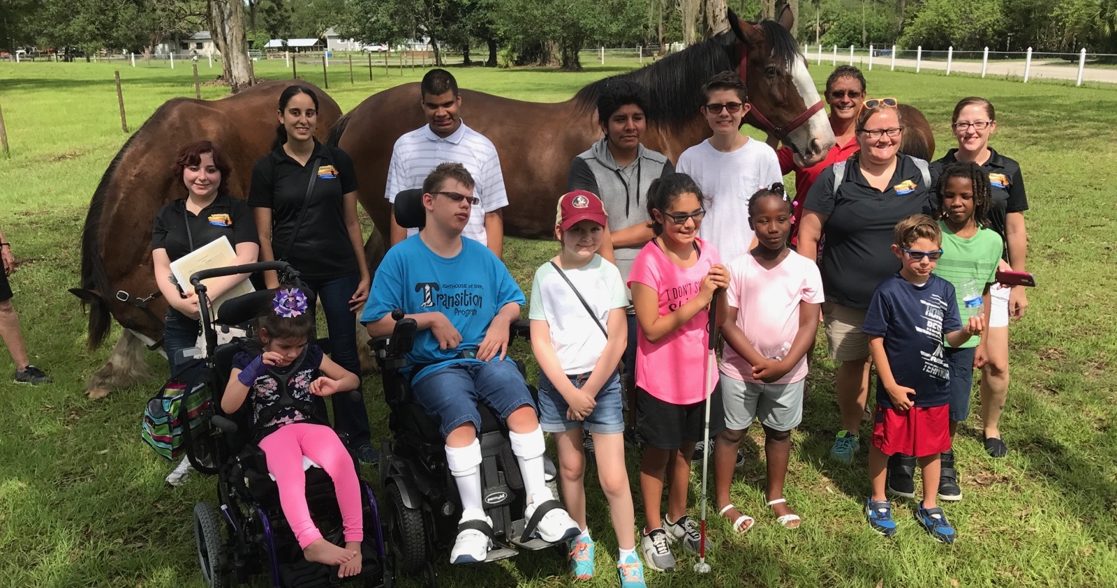 Summer campers and staff standing front of two horses.