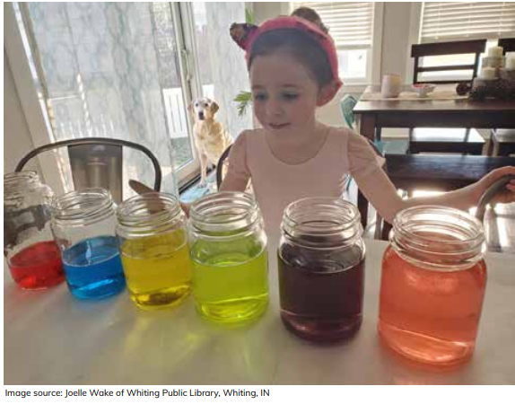 A child looking at jars filled with different colored water.