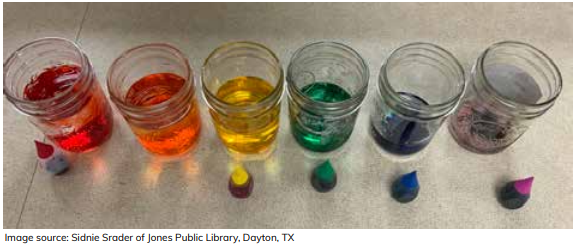 Jars containing different colored water and food coloring bottles beside each.