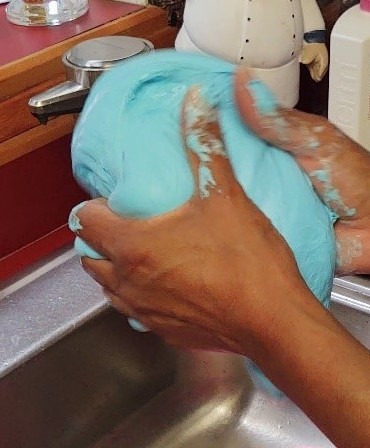 Pair of hands holding a ball of blue slim.